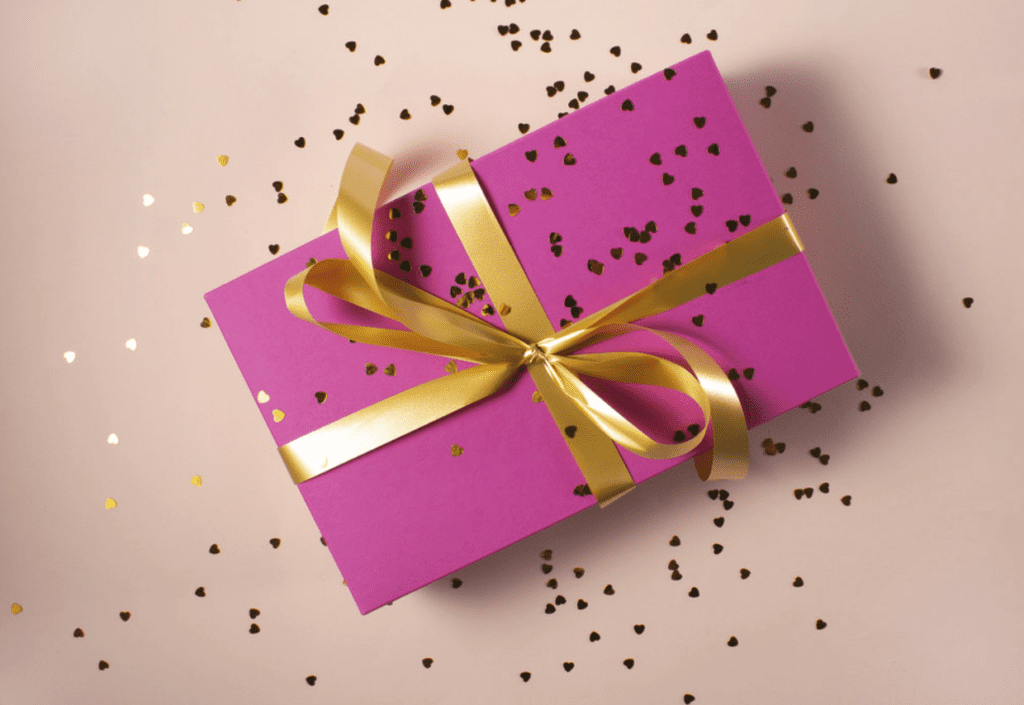 A pink present with a gold ribbon wrapped around it